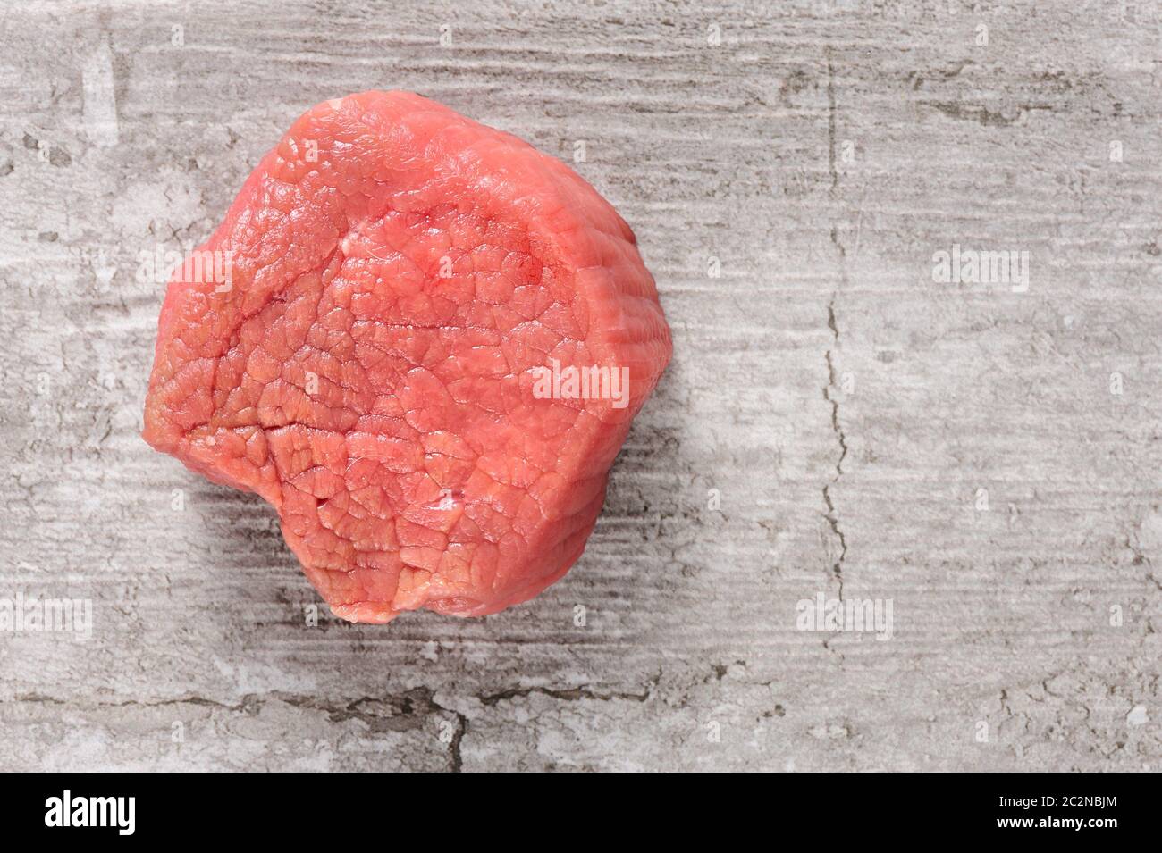 Stück rohes RINDFLEISCHFLEISCH auf gebrochenen Stein oder Beton Hintergrund Stockfoto