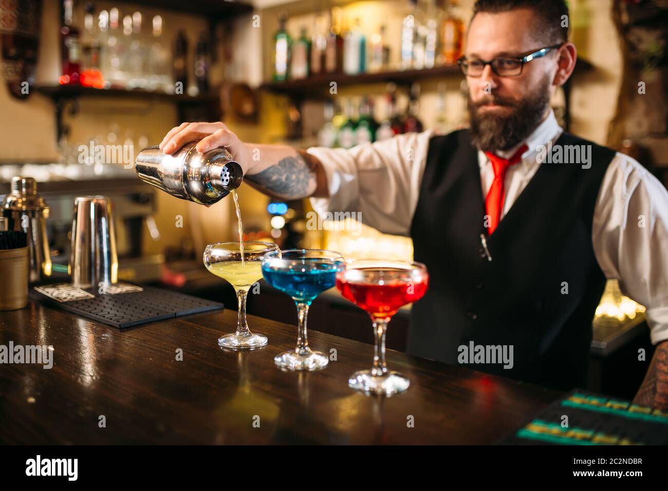 Barkeeper mit Shaker, der hinter einer Bar im Nachtclub alkoholische Cocktails zubereitet Stockfoto