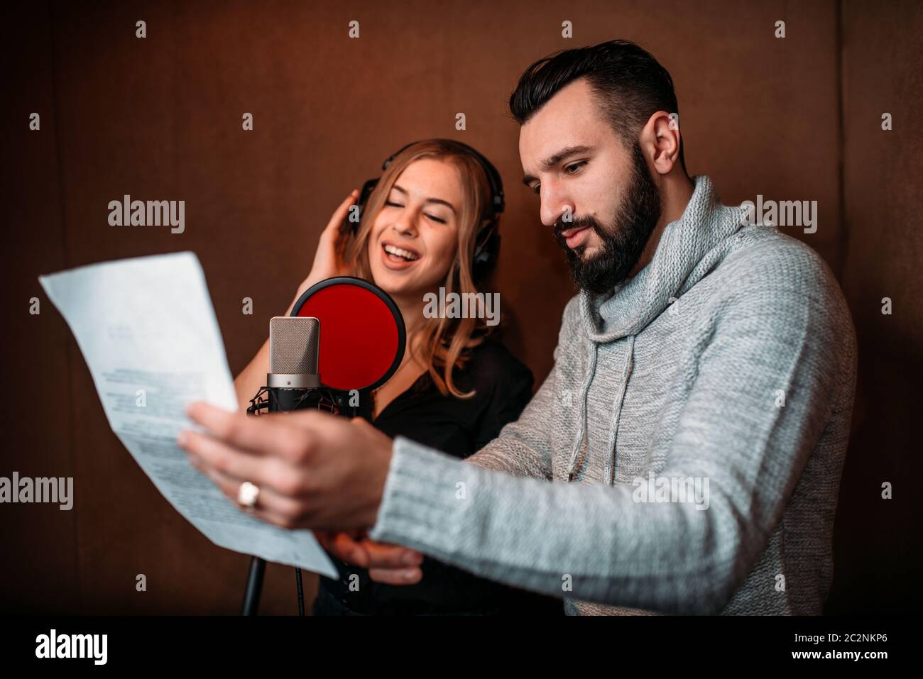 Musikproduzent zeigt Text Sängerin in Kopfhörer, Song-Rekord im Musikstudio. Sängerin Aufnahme audio-Track. Professionelle digitale sound Stockfoto