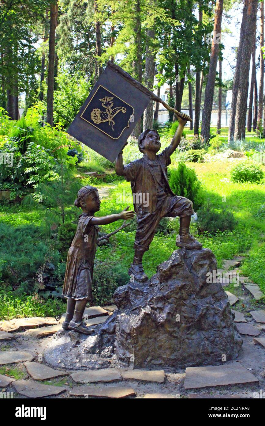 Bronze Skulptur des kleinen Jungen mit Flagge und Mädchen, die in den Berg in Stadtpark Stockfoto