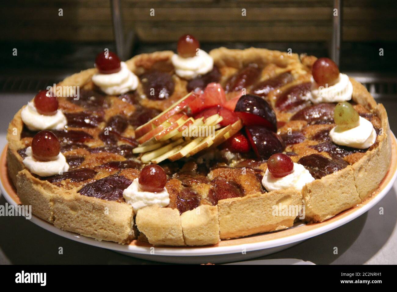 Festlicher Kuchen mit Beerenmarmelade, frischen Trauben und Äpfeln. Köstliches natürliches Dessert. Apfelkuchen Stockfoto