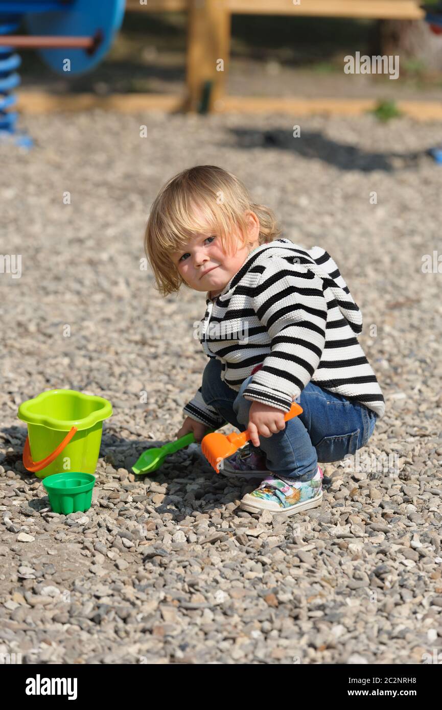 Nettes Kleinkind Baby Mädchen spielen mit Schaufel auf Spielplatz Stockfoto