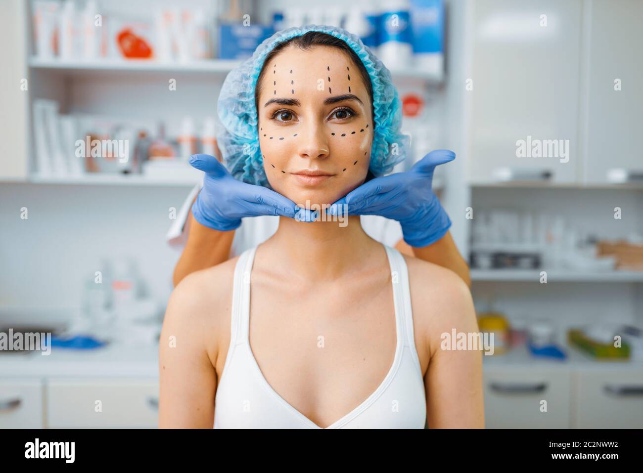 Kosmetikerin und Patientin mit Markern im Gesicht. Verjüngungsverfahren in Kosmetiksalon. Kosmetische Chirurgie gegen Falten, Vorbereitung auf Stockfoto
