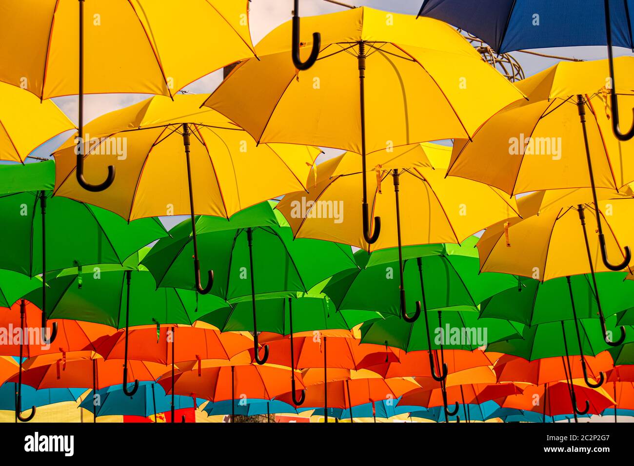 Knallfarbener hängender Regenschirm als tropische Sommerdeko Stockfoto