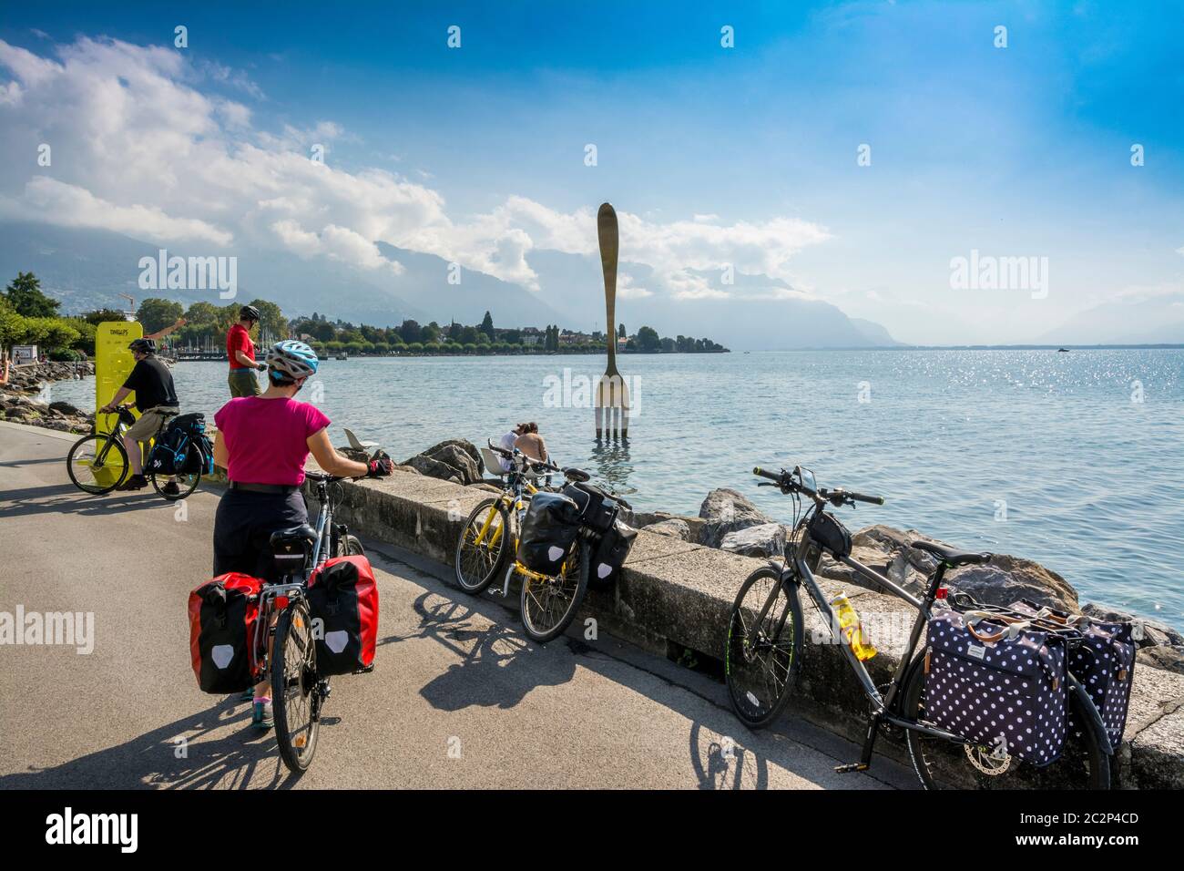 Skulptur einer großen Gabel von Jean-Pierre Zaugg am Ufer des Leman-Sees in Vevey mit Radfahrern, die die Aussicht genießen. Schweiz Stockfoto