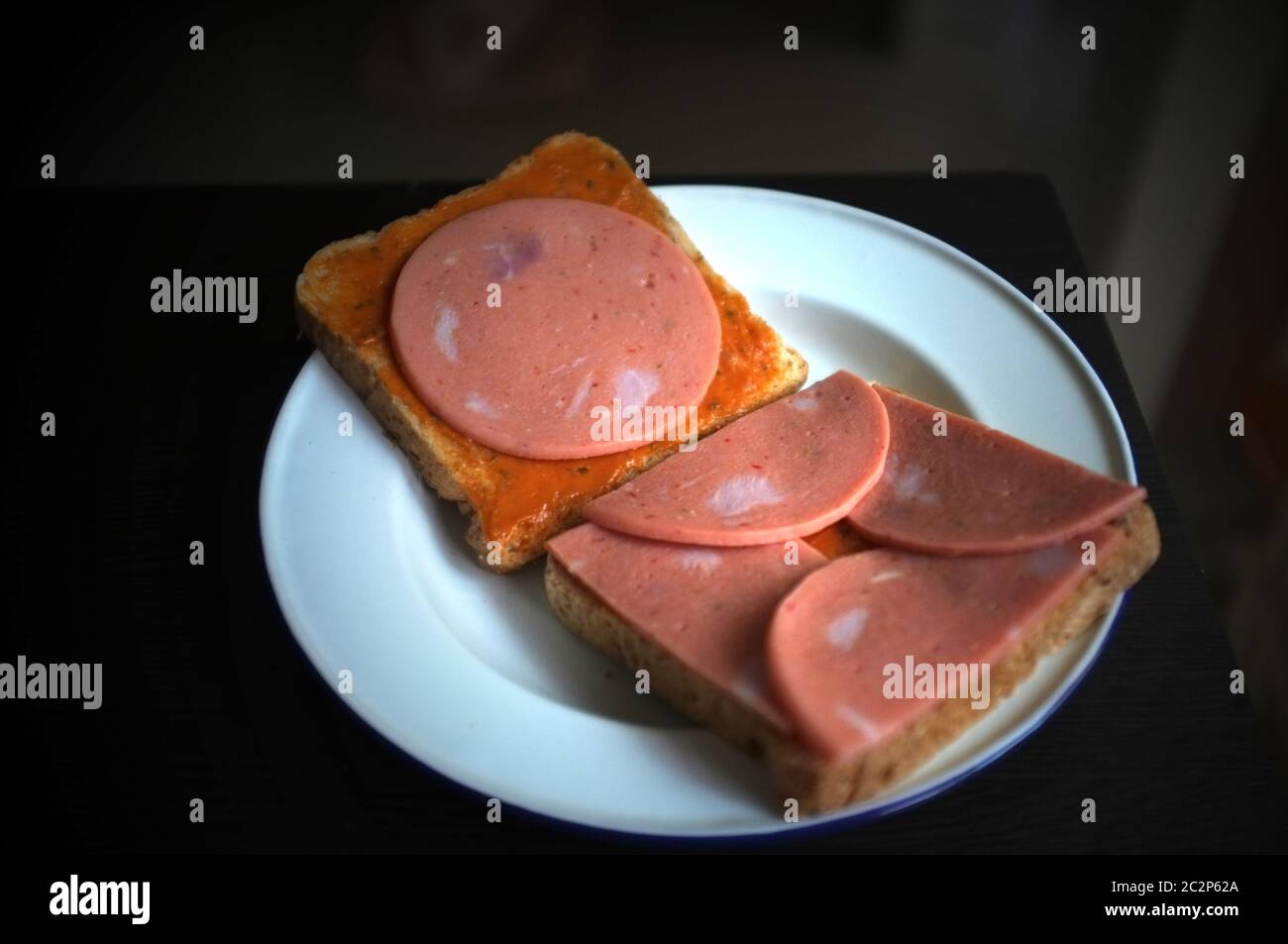 Brot mit Schweinshaxe auf weißer Platte schneiden Stockfoto