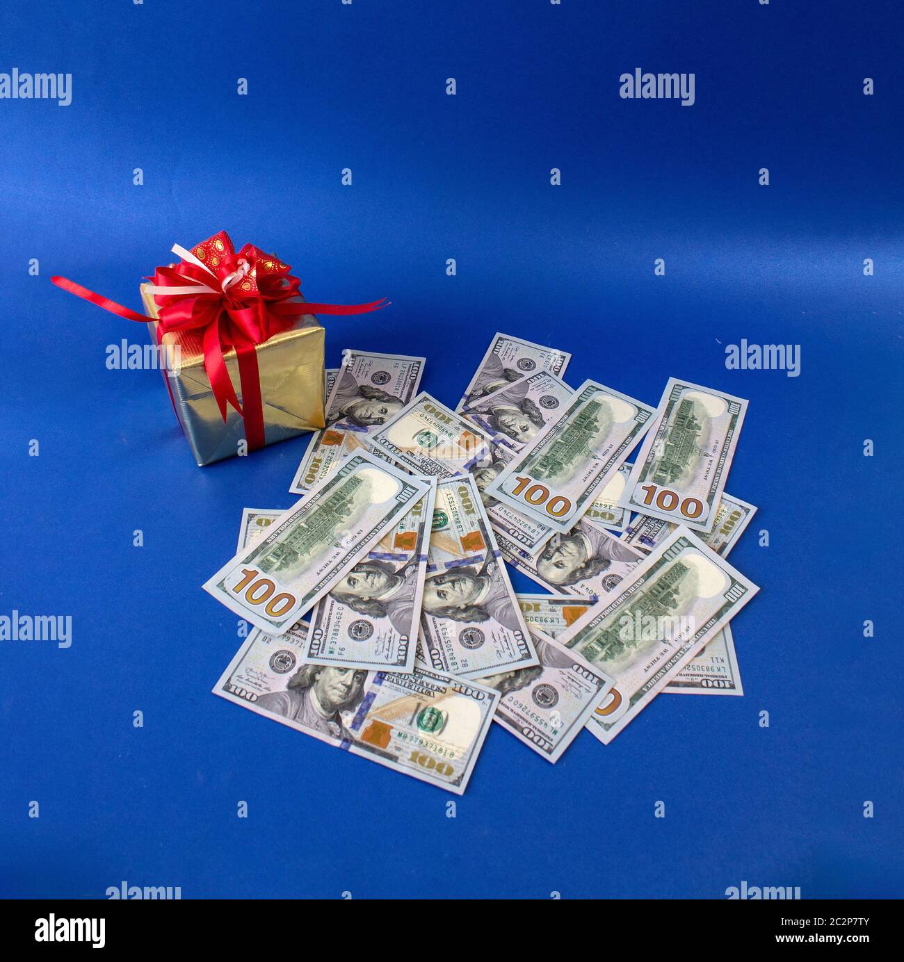 Dollar zusammen mit einem Geschenk, ein Symbol der Krise, Venality, Reichtum, Horten und Armut. Foto auf blauem Hintergrund Stockfoto