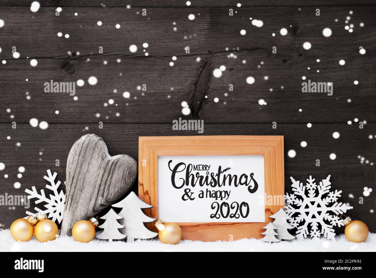 Englisch Kalligraphie Frohe Weihnachten und guten Rutsch ins Jahr 2020.  Golden Christmas Ornament wie Kugel, Herz und Baum. Graues Holz-  Hintergrund mit Schnee und Snowflak Stockfotografie - Alamy