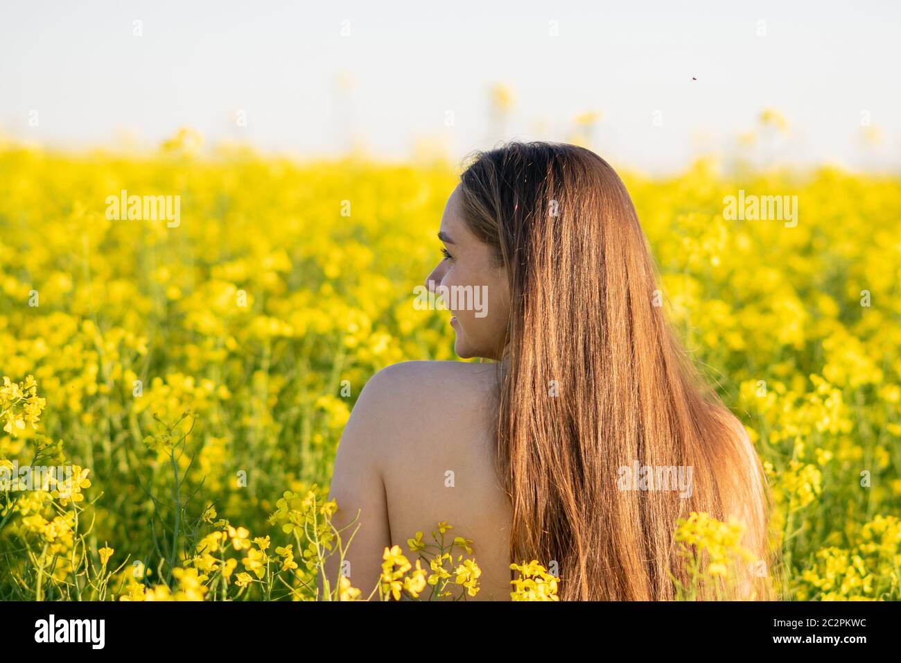 Schönes Mädchen in einem Rapsfeld, mit einer offenen Schulter. Stockfoto