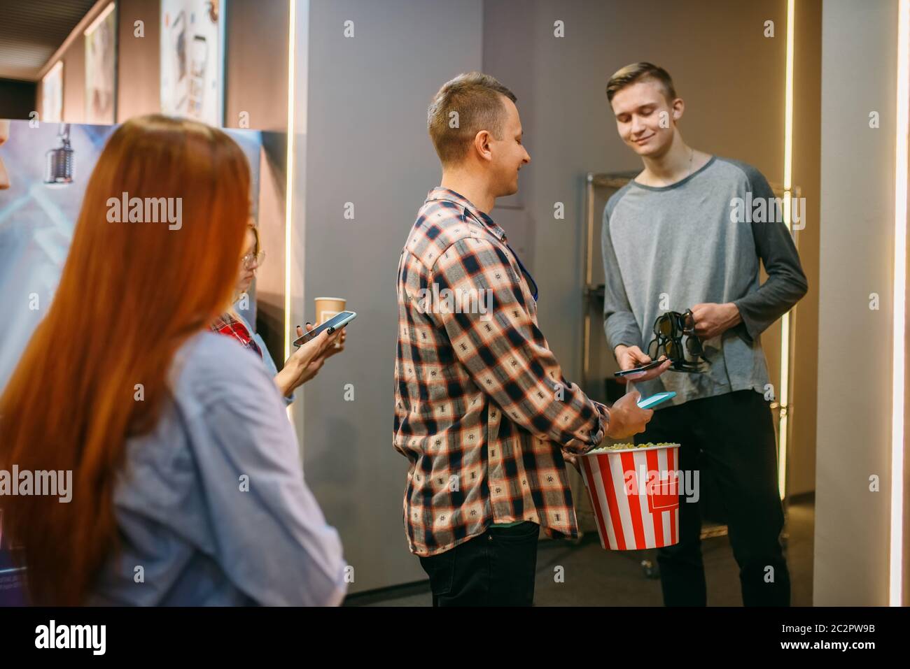 Publikum scans Tickets auf den Handys vor dem Showtime in Kino, Ansicht von hinten. Männliche und weibliche Jugend in Kino Stockfoto