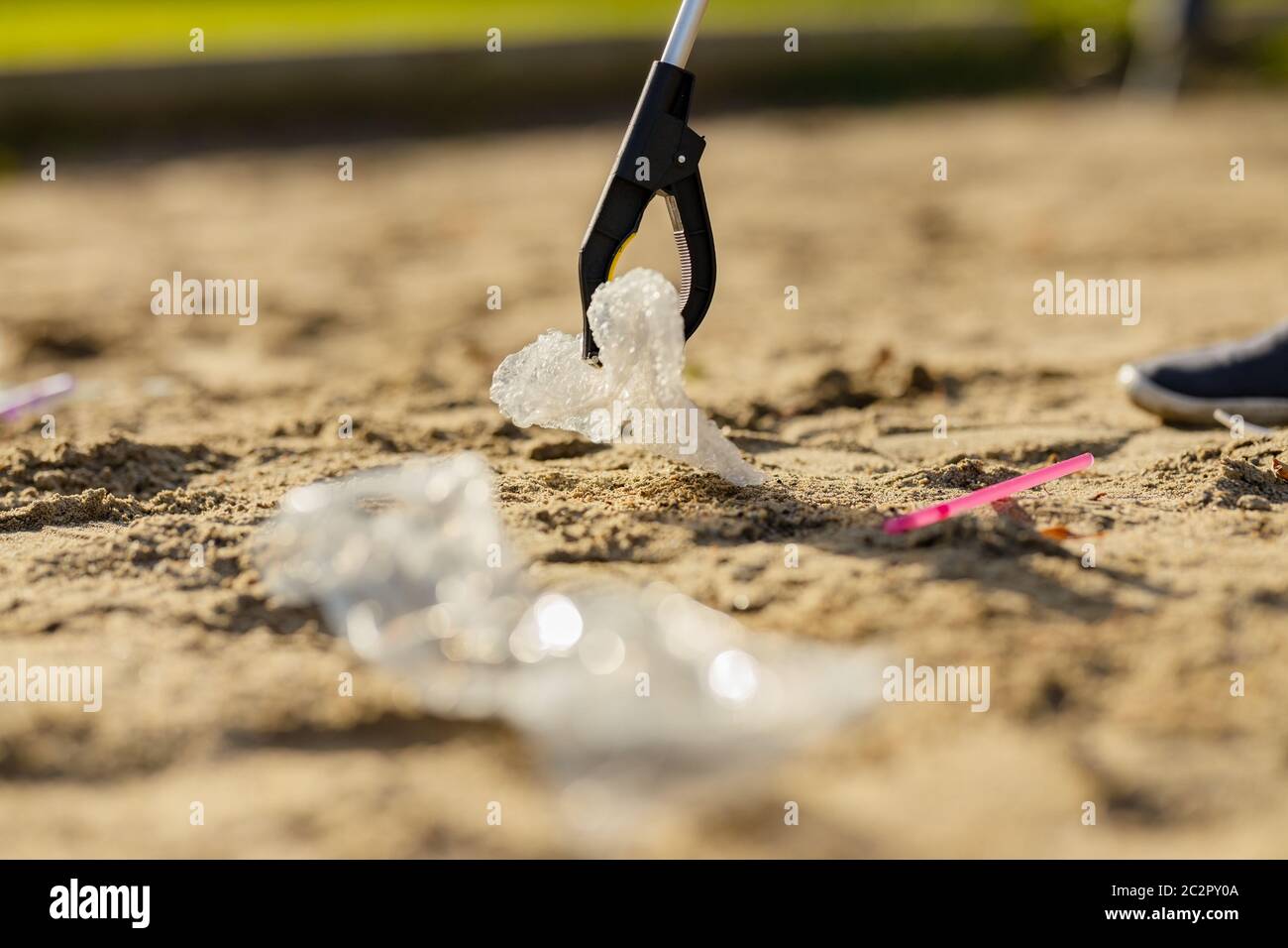 Nahaufnahme eines Freiwilligen, der am Strand Müll mit einem Grabber abholt Stockfoto