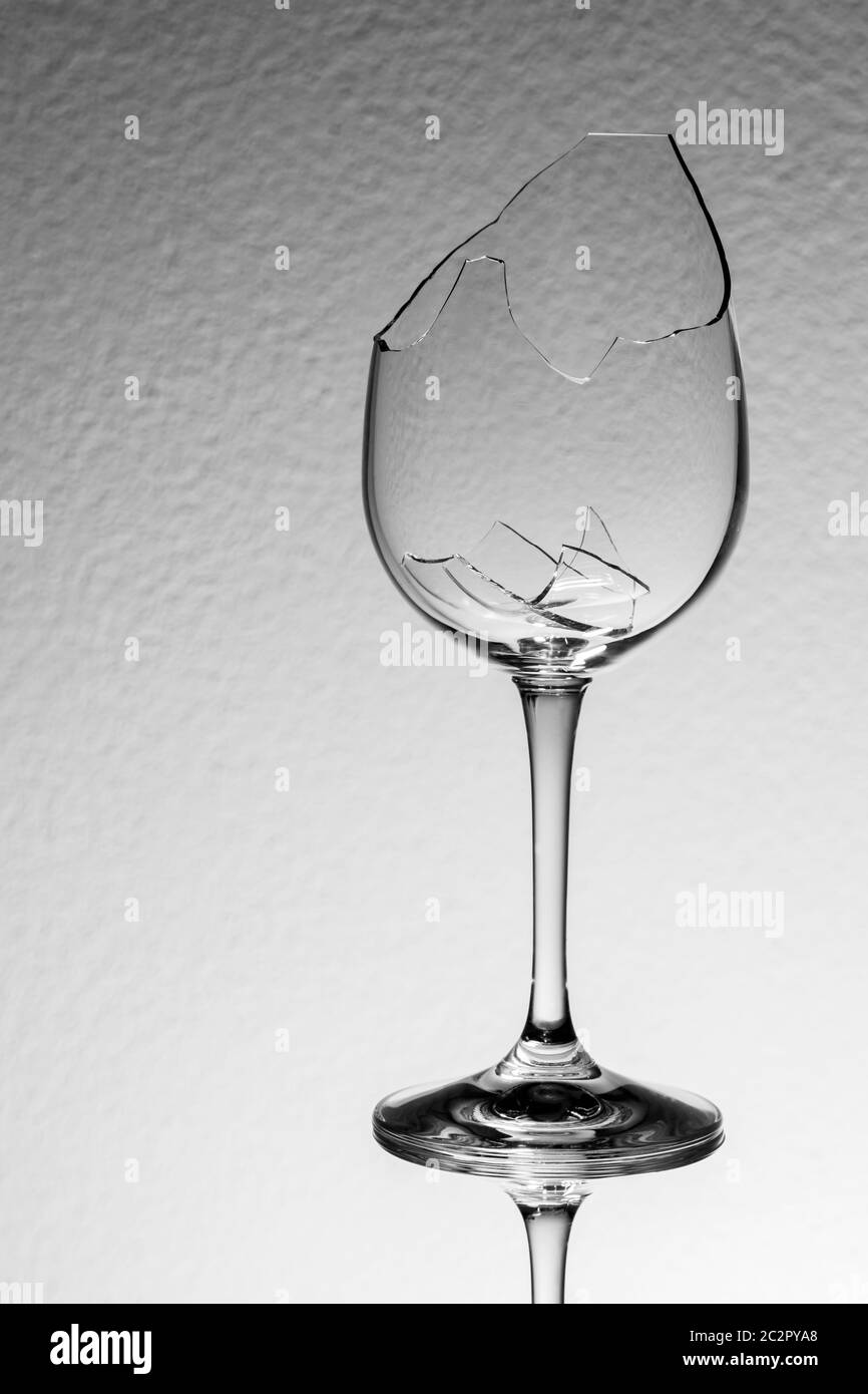 Studio Nahaufnahme eines gebrochenen Weinglases mit gebrochenen Fragmenten vor rauem Hintergrund. Stockfoto