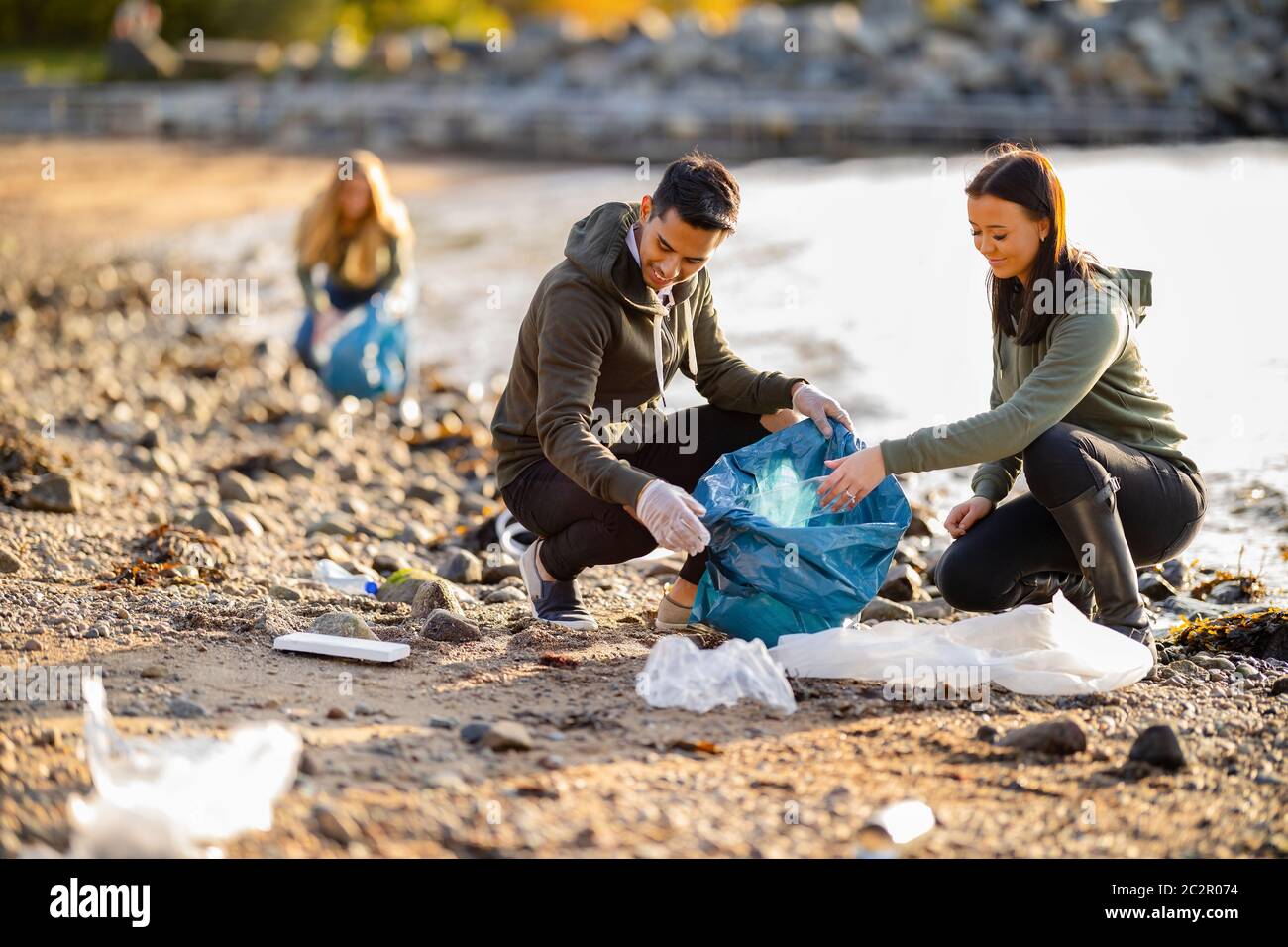Team von engagierten und lächelnden Freiwilligen sammeln Müll am Strand Stockfoto