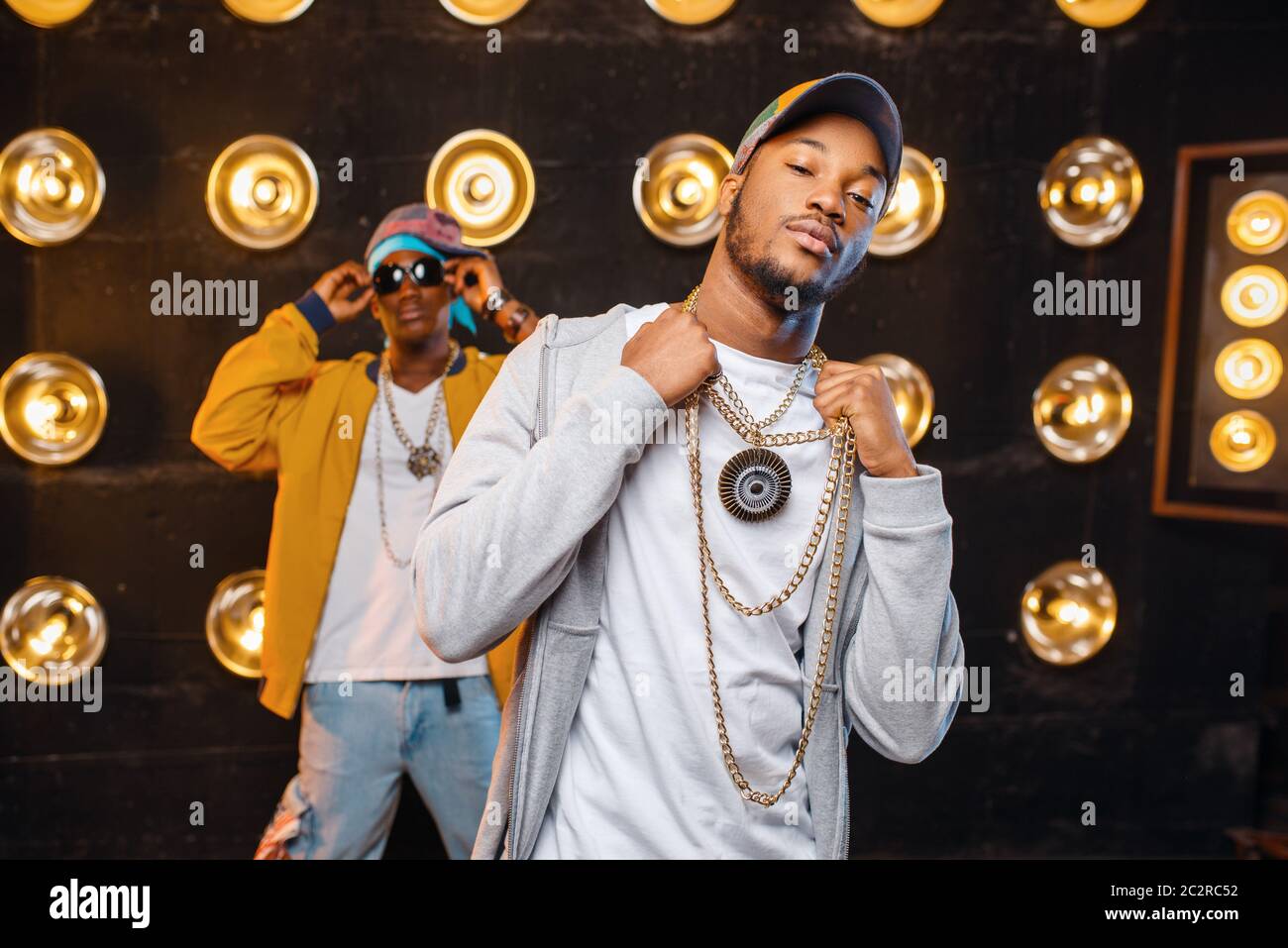 Zwei schwarze Rapper in Caps auf der Bühne mit Scheinwerfern für den Hintergrund. Rap Darsteller auf der Bühne mit Beleuchtung, U-Musik, Urban Style Stockfoto