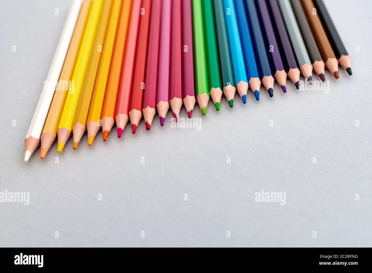 Eine Auswahl von Farbstiften, die in einer diagonalen Linie von weiß bis schwarz platziert sind Stockfoto