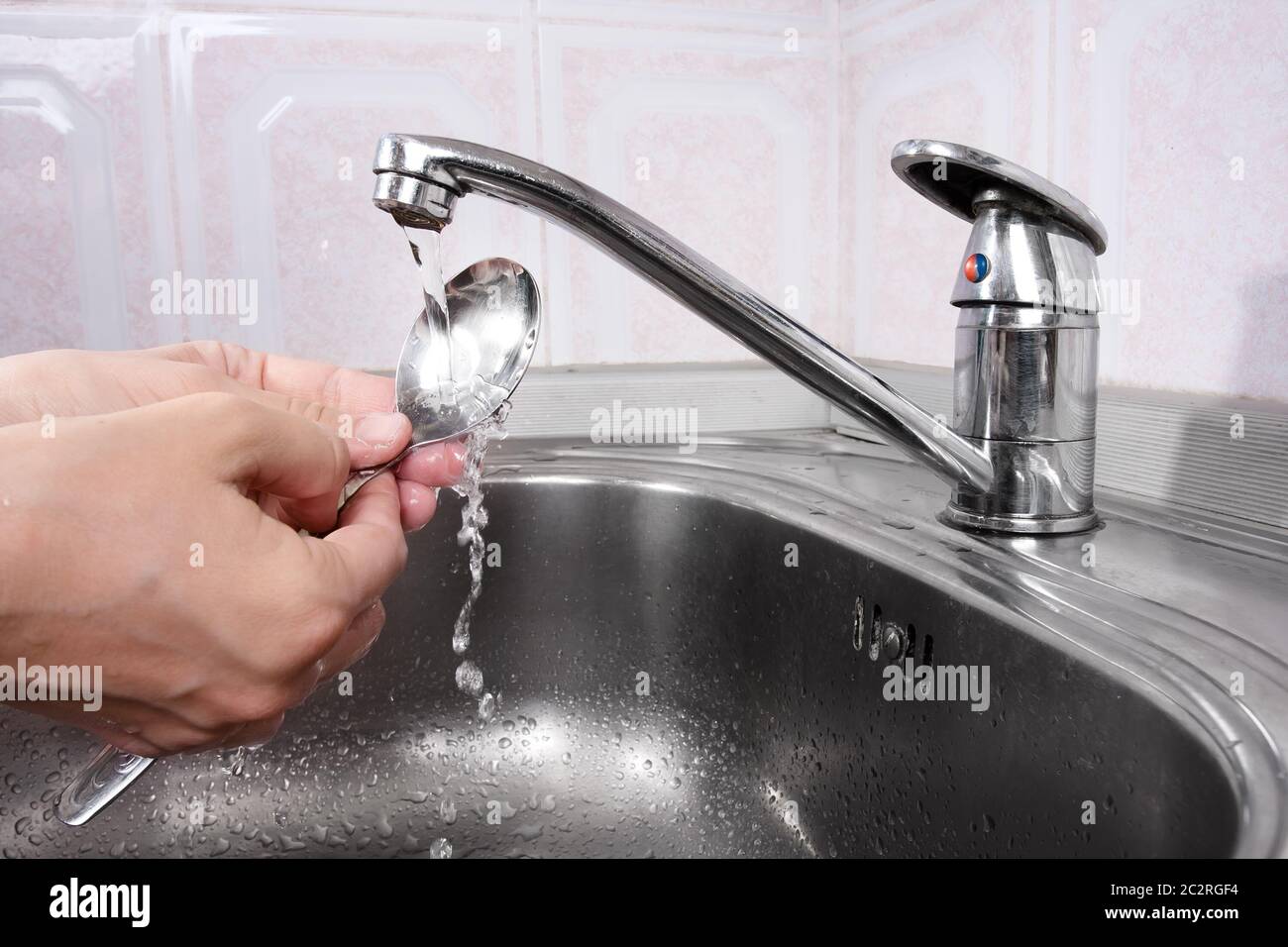 Frauenhände waschen das Geschirr im Waschbecken Stockfoto