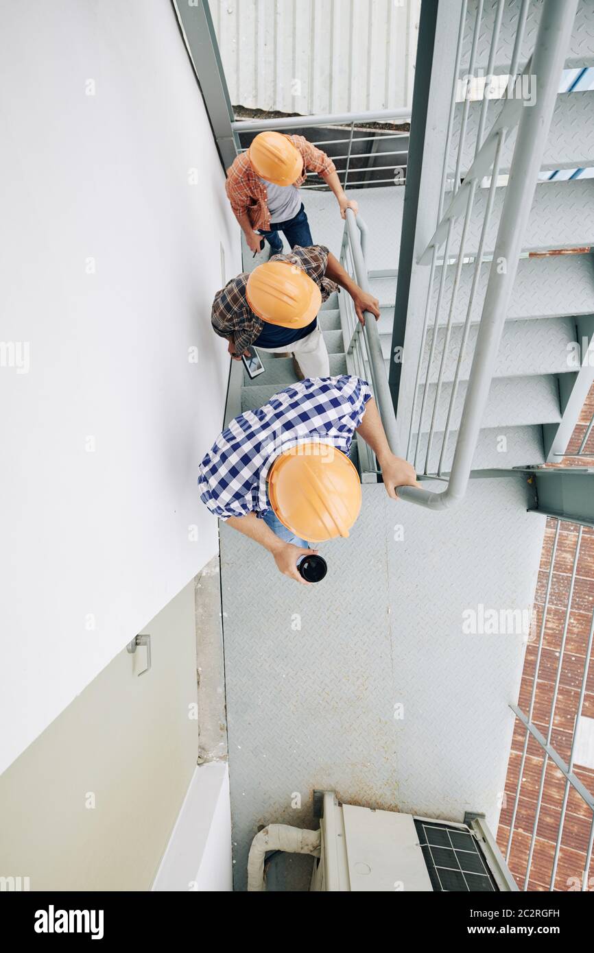 Vertikale Ansicht von oben Aufnahme von drei nicht erkennbaren Bau-Spezialisten tragen Hardhats gehen nach oben, kopieren Raum Stockfoto