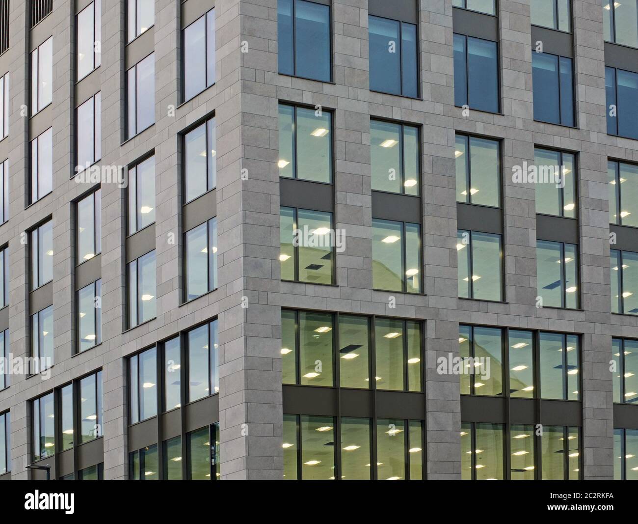 Die Ecke eines großen modernen Bürogebäudes in der Dämmerung mit Licht durch die Fenster Stockfoto