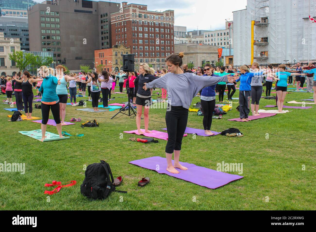 Eine große Gruppe von Menschen macht einen Yoga-Unterricht auf einer städtischen Wiese in Ottawa, Ontario, Kanada Stockfoto