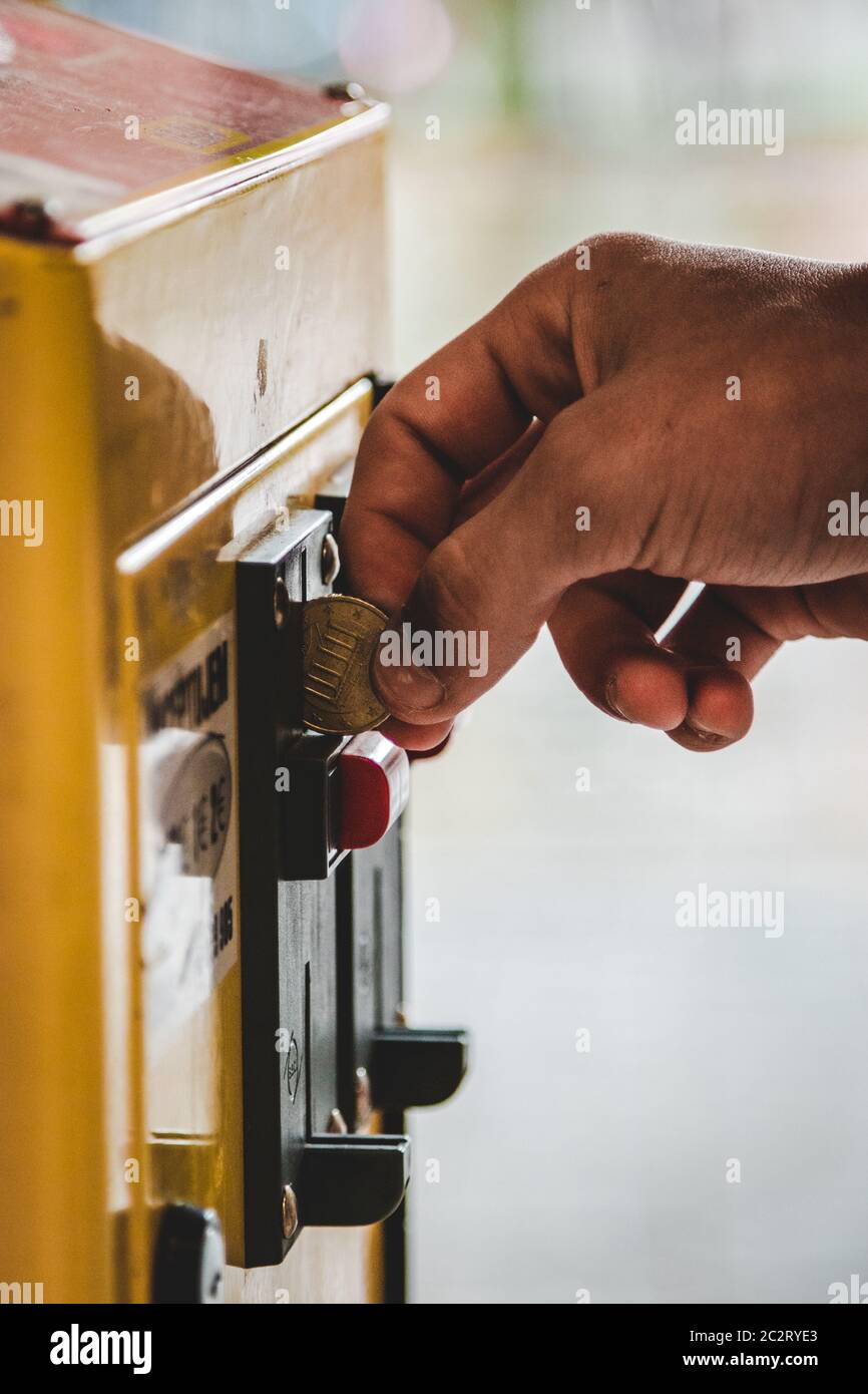 Weiße Hand Putting Münze in Spielautomaten bei sonnigen Tag Stockfoto