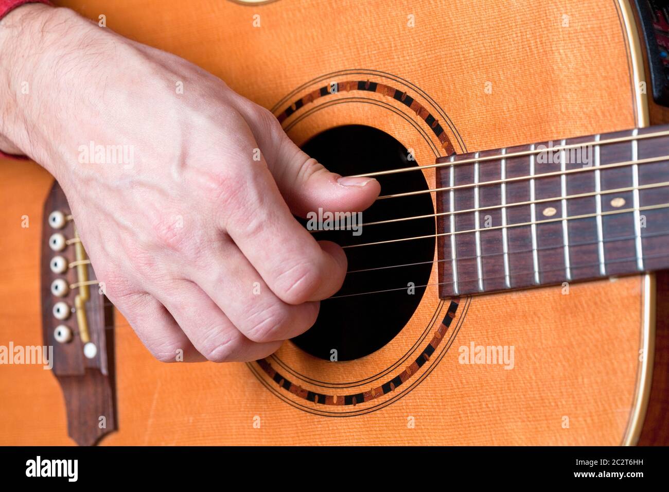 Finger eines Gitarristen, der akustische Gitarre spielt. Stockfoto