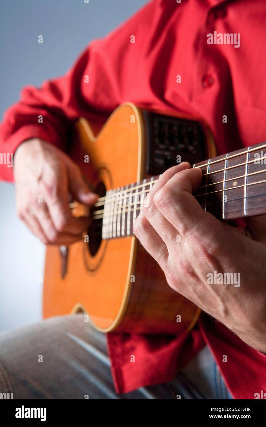 Finger eines Gitarristen, der akustische Gitarre spielt. Stockfoto