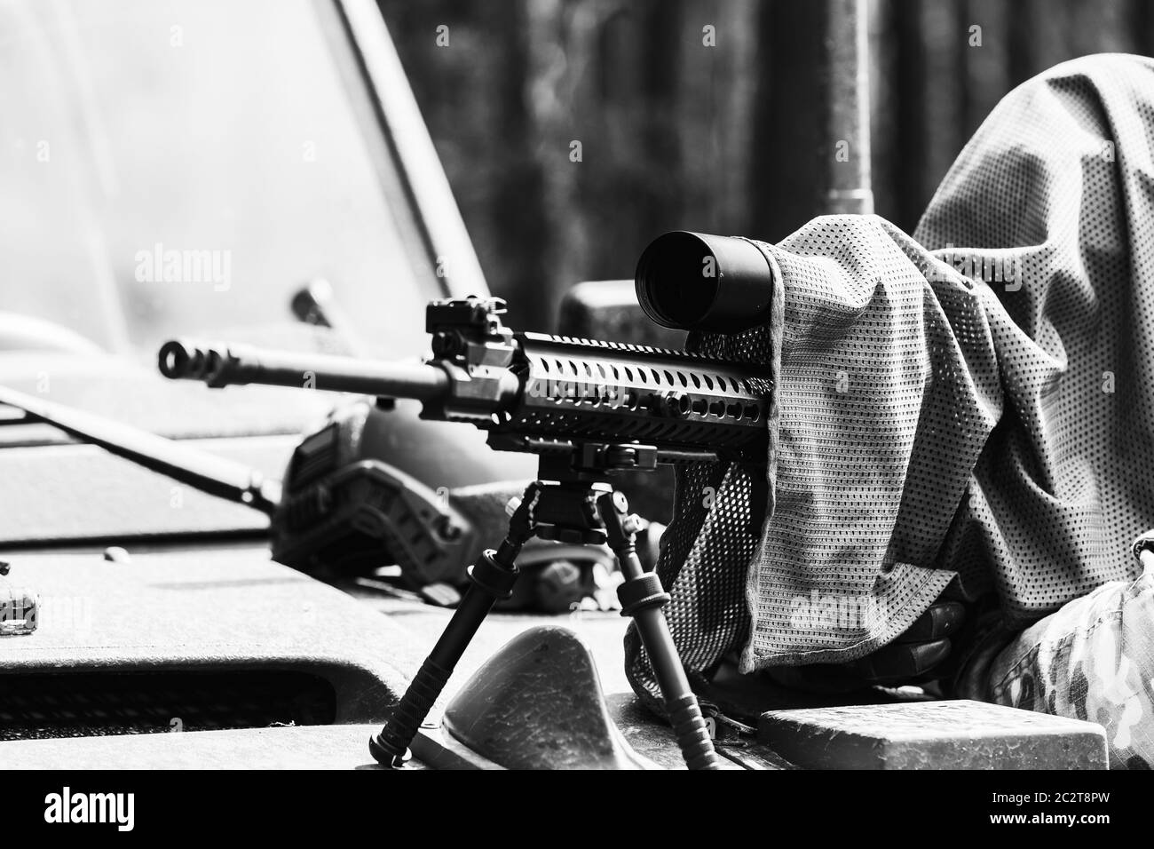 Militärmann in Tarnuniform mit Gewehr. Ausgerüstet Scharfschützenschießen mit Gewehr. Ein maskierter Scharfschütze zielt auf ein Ziel. Scharfschütze mit einem Gewehr. Stockfoto