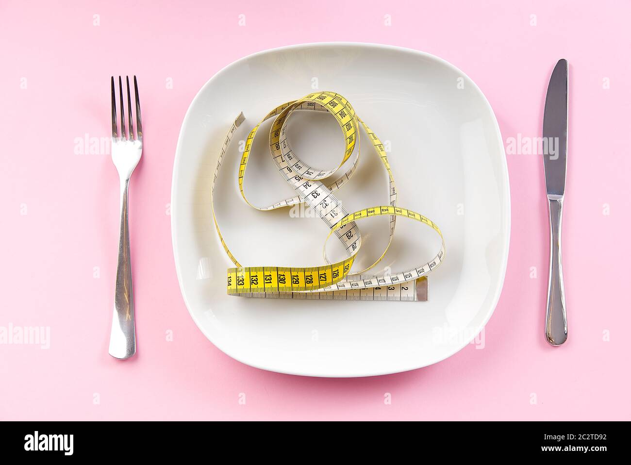 Weight Loss Measuring Tape auf weißen Platte, Konzept der gesunden Ernährung. Rosa Hintergrund. Stockfoto