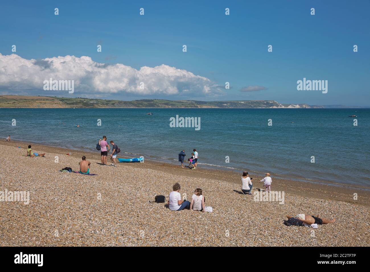 Menschen und Touristen genießen sonnigen Sommertag am Strand in Weymouth, Dorset, Großbritannien Stockfoto