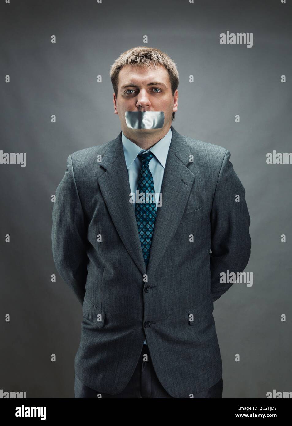 Mann mit Mund und Händen fallenden Klebeband verhindert Rede, isoliert auf grau Stockfoto