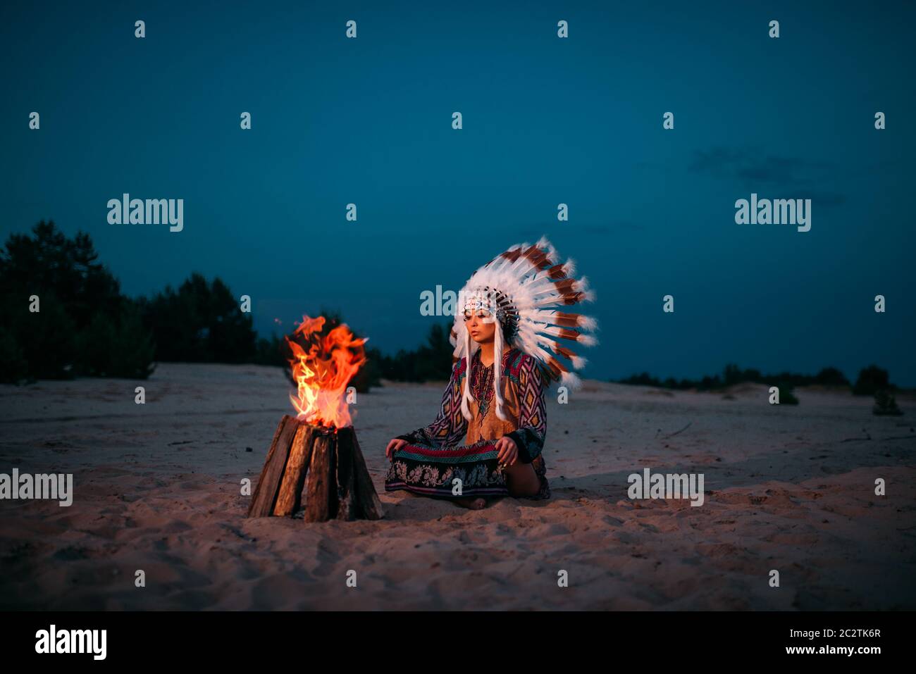 Junge Indianische Frau gegen Feuer, Cherokee, Navajo. Kopfschmuck aus Federn von Wildvögeln. Nacht Ritual Stockfoto