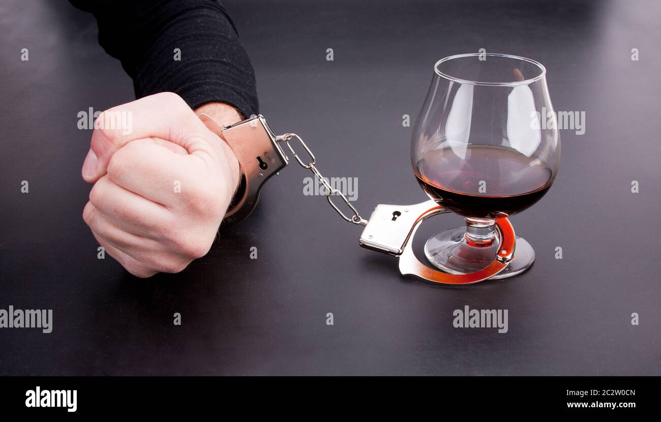 Hand von Handschellen, Glas Alkohol gesperrt. Stockfoto