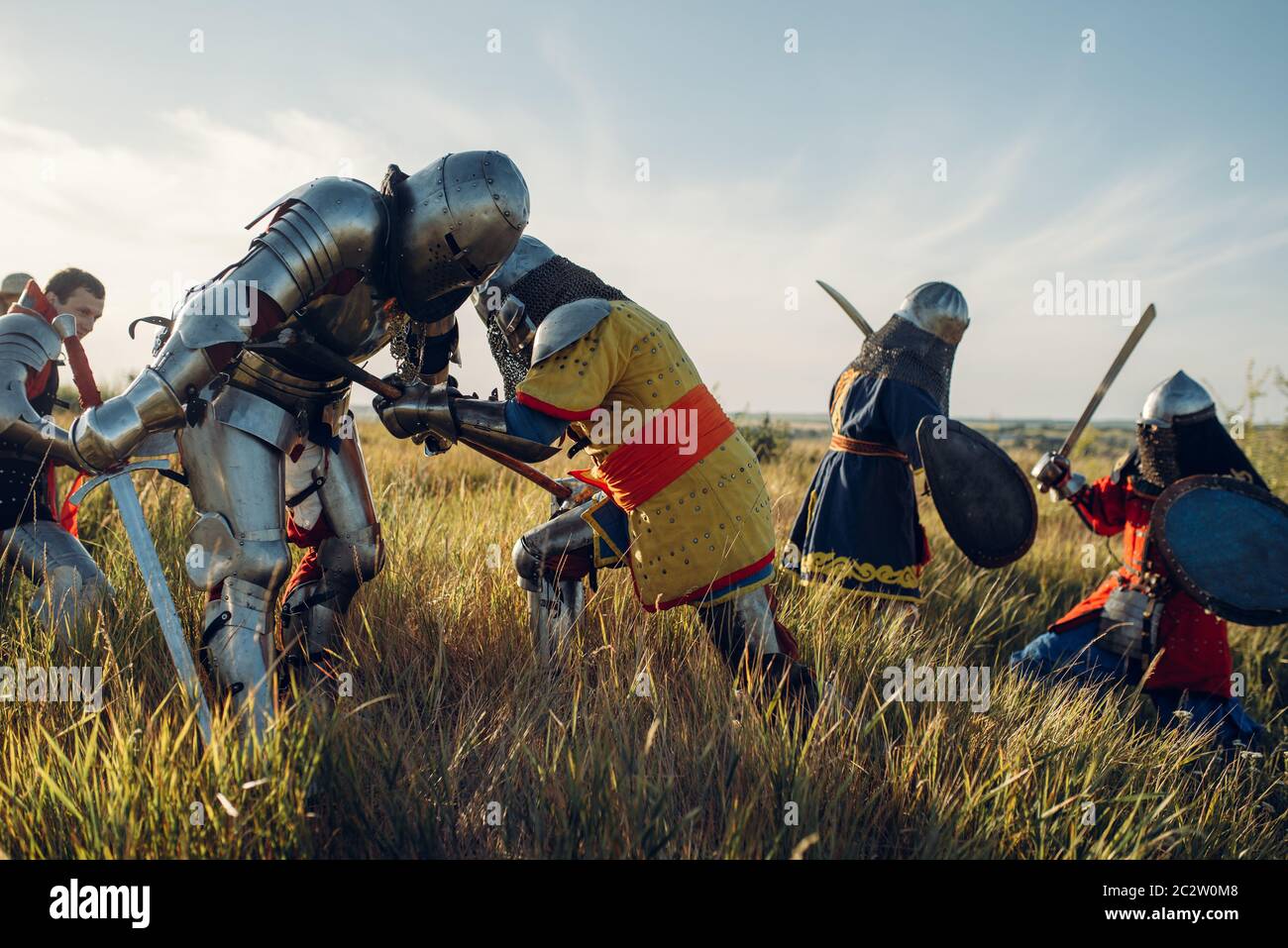 Mittelalterliche Ritter in Rüstung und Helme kämpfen mit Schwert und Axt, große Schlacht. Gepanzerte alte Krieger in Rüstung posiert auf dem Feld Stockfoto