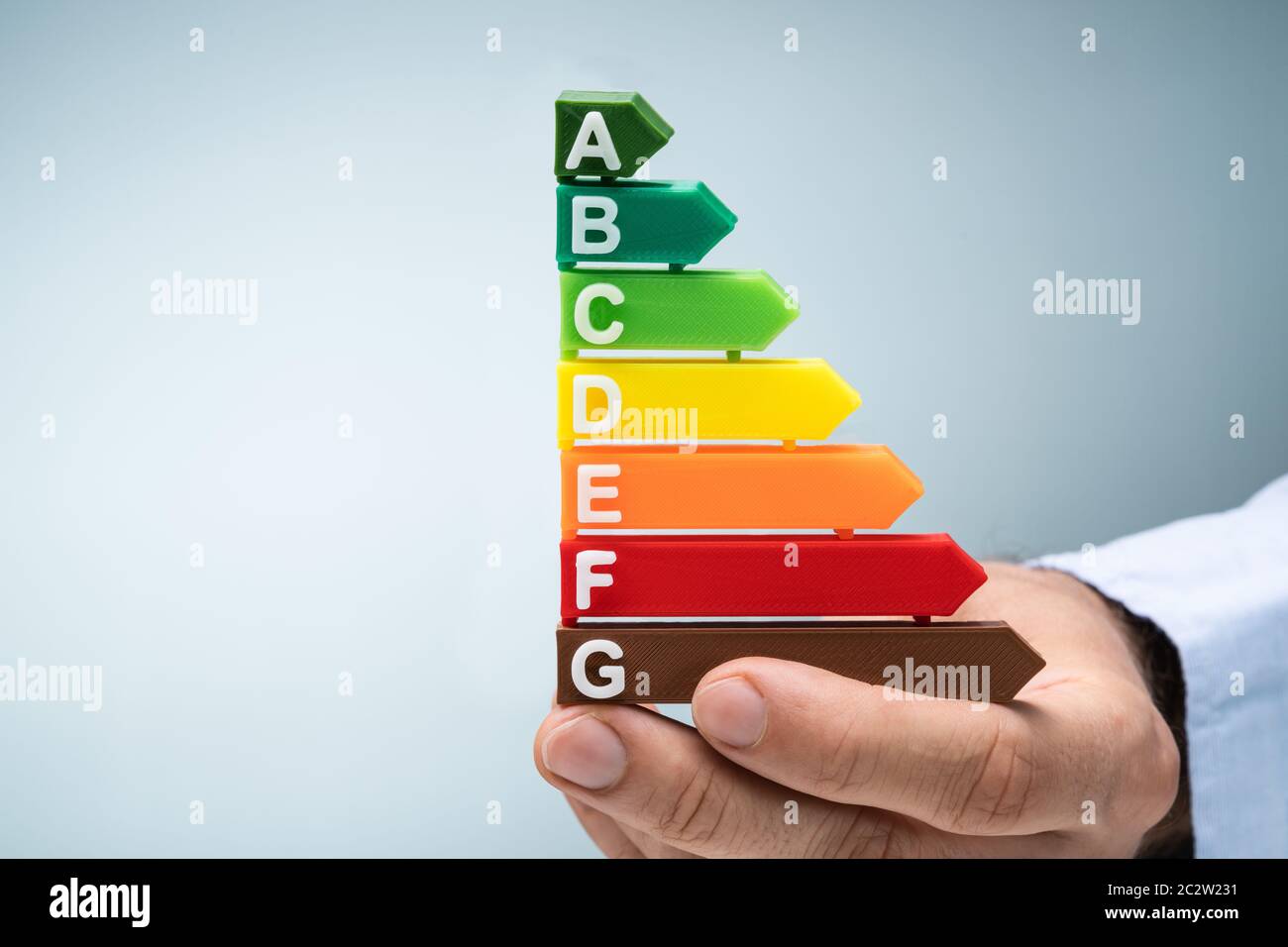 Close-up In eines Mannes Hand Kunststoff Energieeffizienz Graph vor blauem Hintergrund Stockfoto