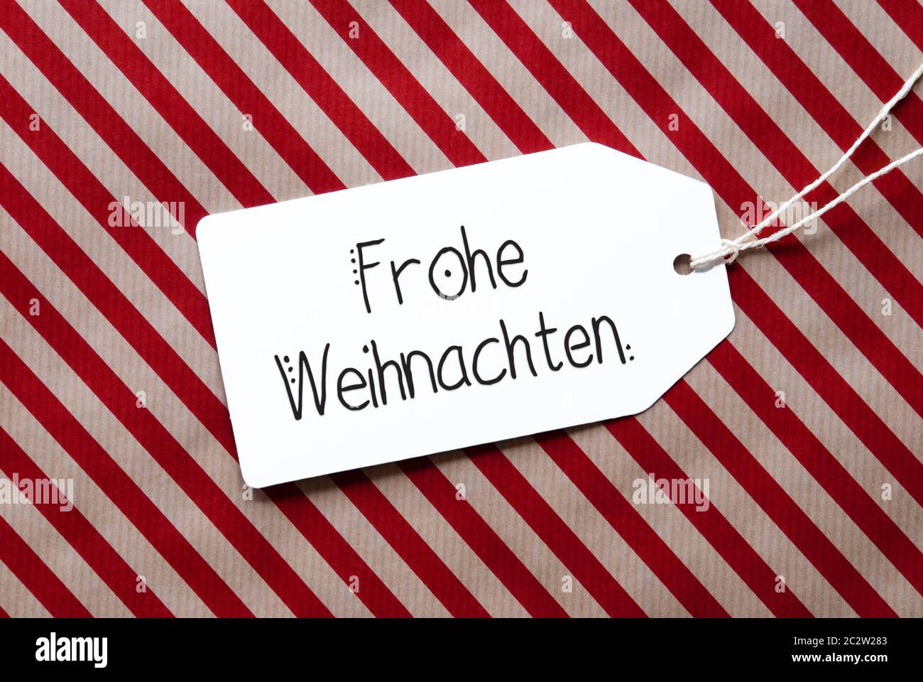 Etikett mit Deutschen Kalligraphie Frohe Weihnachten, Frohe Weihnachten. Rote Verpackung Papier als Hintergrund Stockfoto