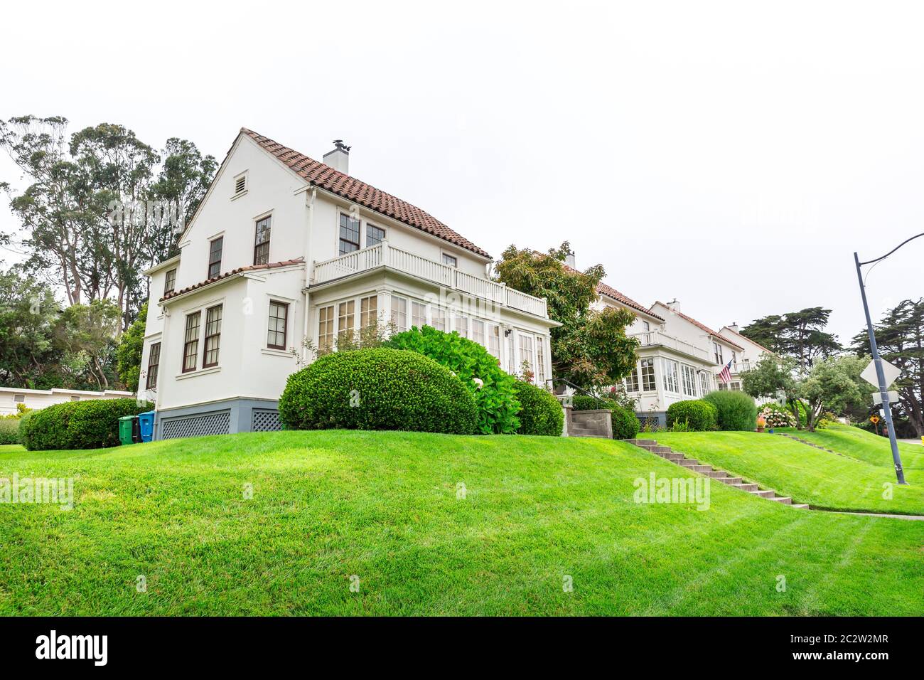 Sanft schräg anliegendem Rasen vor dem weißen gemütlichen Haus. Außenarchitektur des Anwesens. Stockfoto