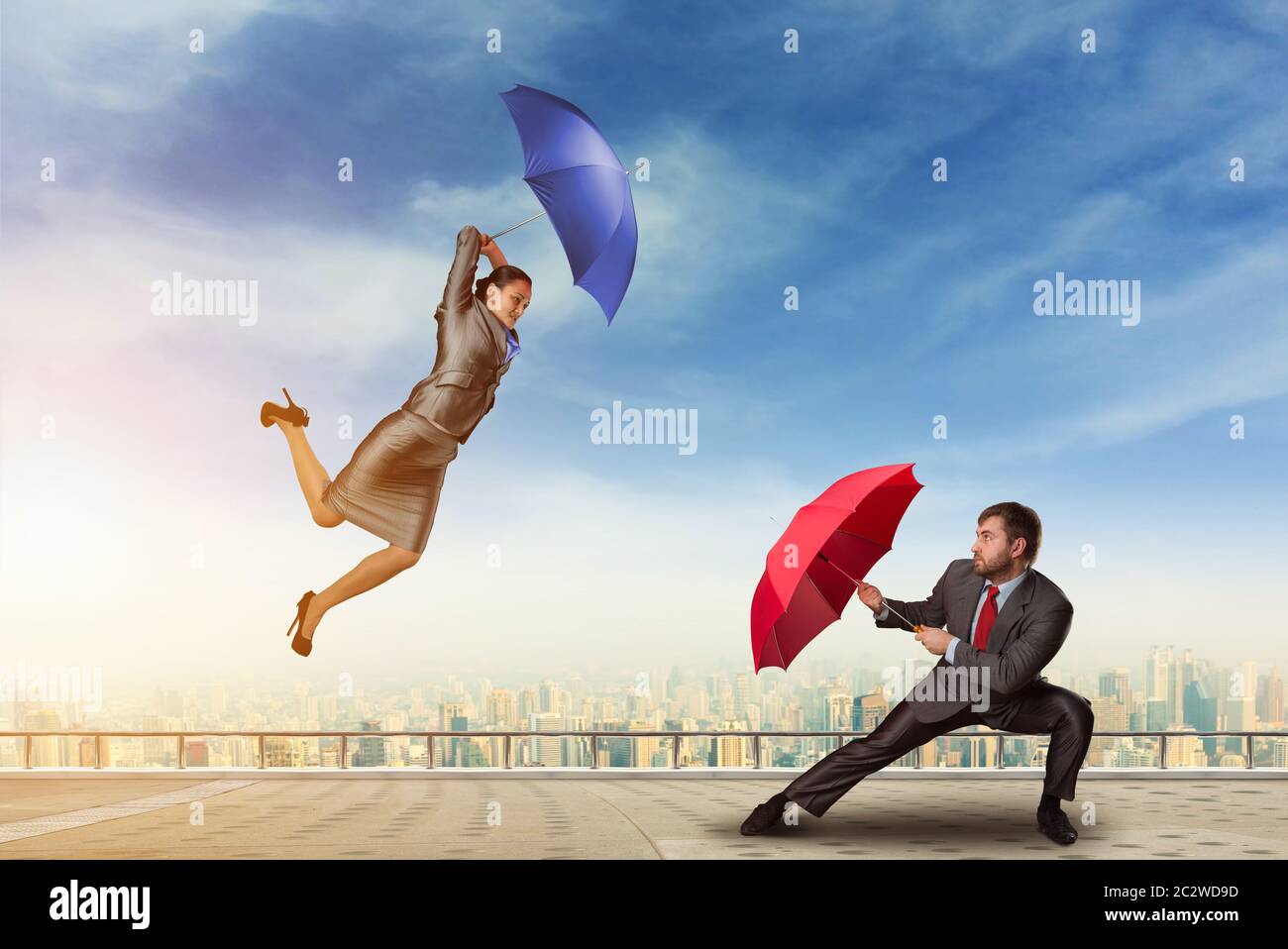 Business-Leute kämpfen mit Sonnenschirmen auf dem Dach Stockfoto