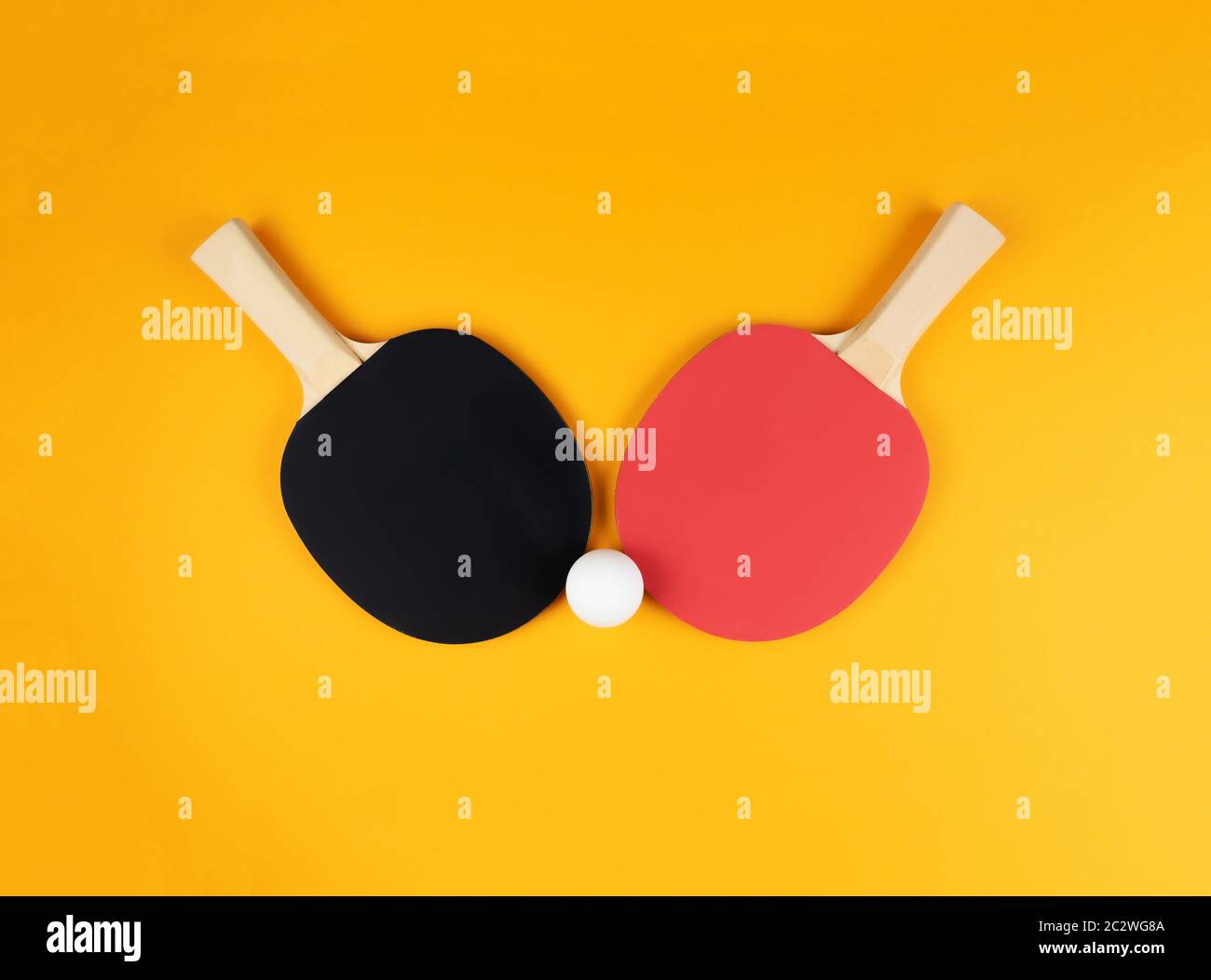 Direkt über Schuss von zwei Tischtennisschlägern und Ball auf orangenen Hintergrund. Stockfoto