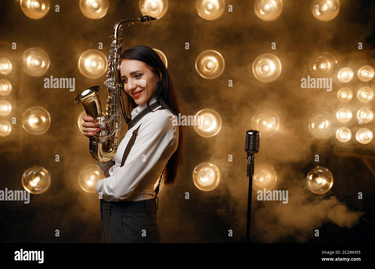 Saxophonistin posiert mit Saxophon auf der Bühne mit Scheinwerfern. Jazz-Performer spielt auf der Szene Stockfoto