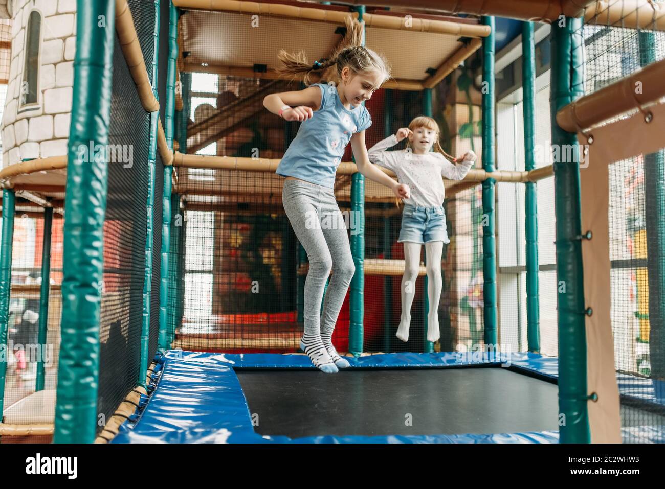 Zwei lustige Mädchen springen auf dem Trampolin, Kinder Game Center. Aufgeregt childs Spaß auf dem Spielplatz im Freien. Kinder spielen in Amusement Center Stockfoto