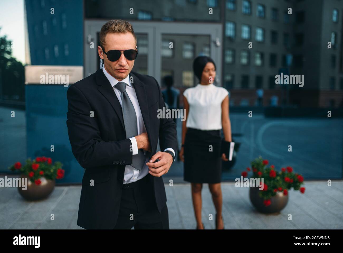 Leibwächter in Anzug und Sonnenbrille, weiblich VIP-Kunde für den Hintergrund. Security Guard ist eine riskante Beruf, professionelle Bewachung, business Personen Protein Stockfoto