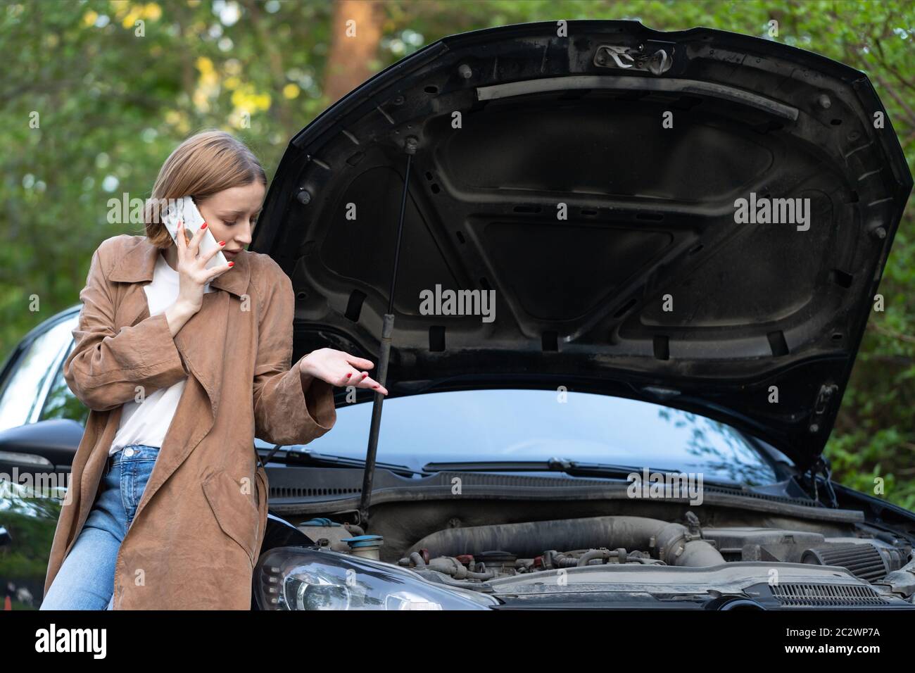 Hilflose Frau Fahrer ruft um Hilfe / Hilfe Blick auf defekte Auto, hielt am Straßenrand. Versteht nicht, was passiert ist. Stockfoto