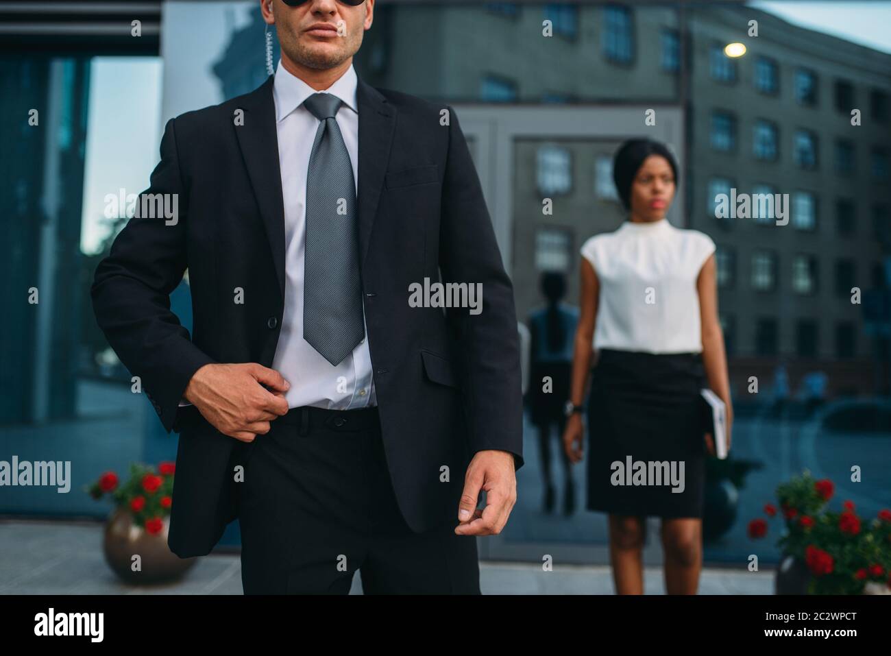 Leibwächter in Anzug und Sonnenbrille, weiblich VIP-Kunde für den Hintergrund. Security Guard ist eine riskante Beruf, professionelle Bewachung, business Personen Protein Stockfoto