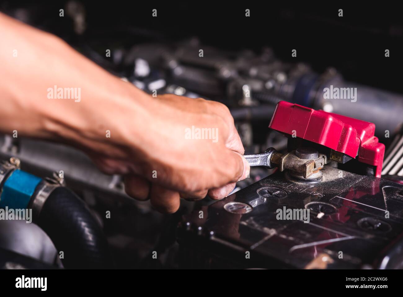 Hand des Techniker Service überprüfen Sie die Batteriespannung und schalten Sie die Batterie Schraube lose in einer Garage. Stockfoto
