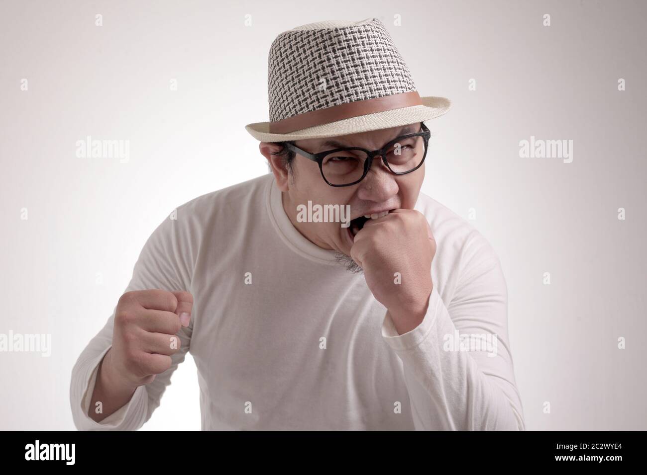 Junger asiatischer Mann trägt weißes Hemd und schreit wegen Wut. Nahaufnahme von Kopf und Schultern Stockfoto