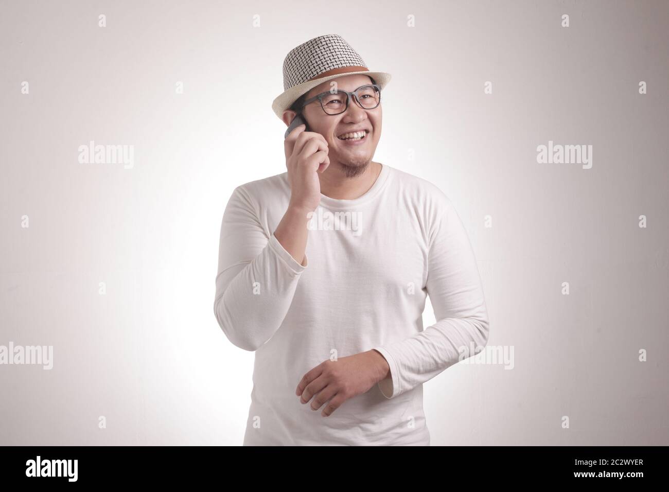 Attraktiver junger asiatischer Mann, der am Telefon spricht, lächelnd lächelnd lächelnde Geste Stockfoto