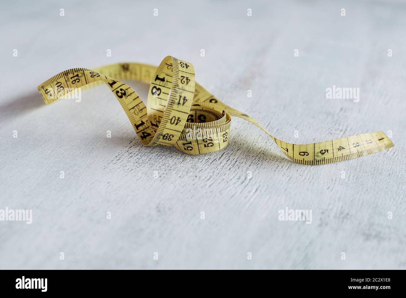 Gelbes Maßband in Zentimetern, gewellt. Maßband auf einem Holztisch Nahaufnahme. Stockfoto