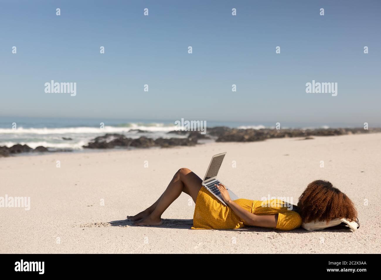 Gemischte Rasse Frau mit Computer am Strand Stockfoto