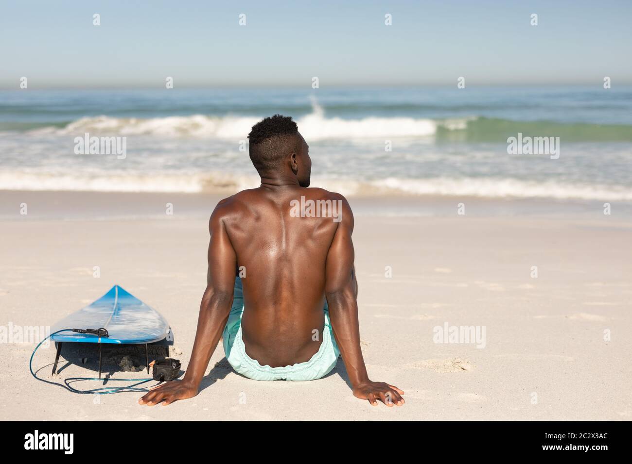 Afroamerikanischer Mann und Surfbrett am Strand Stockfoto