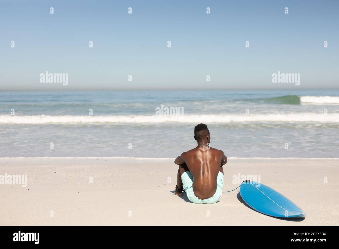 Afroamerikanischer Mann und Surfbrett am Strand Stockfoto